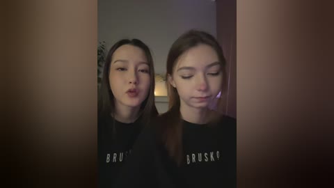 Media: Video of two young Asian women with long black hair, wearing black BRUSK t-shirts, standing in a dimly lit room.