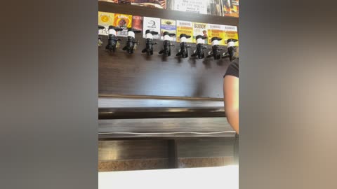 Media: Video of a row of black beer taps mounted on a metallic bar, with a person in a black shirt partially visible on the right.