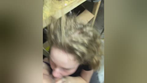 Media: A blurred video of a young woman with light brown hair, performing oral sex on a person, taken from an overhead perspective.