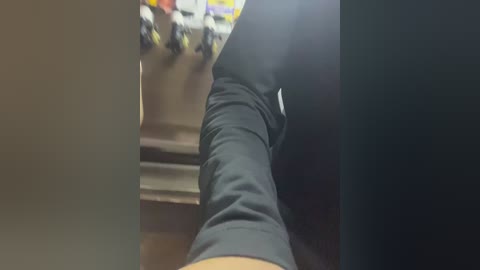 Media: Video of a person wearing black leggings, taken from a low angle, showing a muscular leg. Background includes a blurry shelf with bottles. The setting appears to be a gym or locker room.