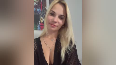 Media: Video of a blonde woman with fair skin, wearing a black lace top, smiling slightly. She has a small tattoo on her neck. The background features abstract art.