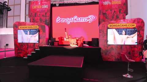 Media: Video of a lively stage with two large screens showing 'BongaCams' branding, a performer dressed in white, and a red backdrop.