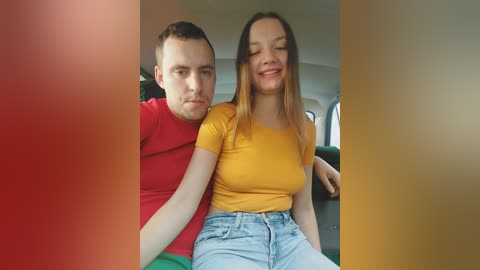 A video of a smiling couple, a man in a red shirt and a woman in a yellow top, sitting closely in a train compartment.