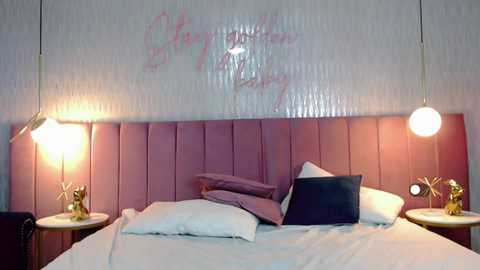 A video of a modern bedroom with a pink tufted headboard, white bedding, two side tables with gold lamp stands, and a pink decorative pillow, against a white wall with pink text.