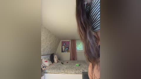 Media: Video of a cluttered, dimly-lit bedroom with a messy bed, beige walls, and a small window with red curtains. A girl with long brown hair in a striped shirt stands in the foreground.