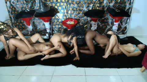 Video of six nude women in various poses on a black mat, against a backdrop of shiny silver confetti and red high heels.