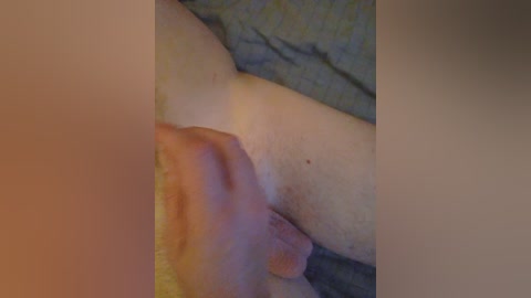 A close-up video of a hand holding a penis, with a blurred background of a bed. The skin tones are light, and the scene is intimate and private.