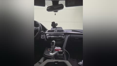 Media: A video of a dimly lit car interior showing a rear view mirror and a driver's seat, with a cellphone visible on the center console.