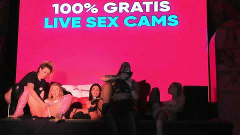 Media: Video of a live sex cam show with four women in various states of undress, against a pink backdrop.