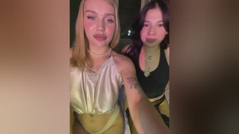 Video of two young women with light skin, one with blonde hair in a white top, the other with dark hair in a black top.