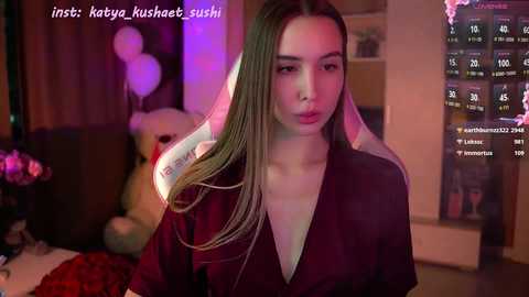 Media: A video of a young Asian woman with long, straight, light brown hair, wearing a deep burgundy robe, indoors with dim lighting, and a live-streaming overlay showing chat messages and numbers.