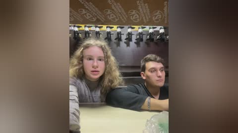 Media: Video of two young men, one with long curly hair, the other with short hair, leaning against a pool table with a wall-mounted dartboard in the background.