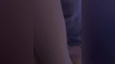 A dimly lit video showing a close-up of a person's bare buttocks and part of a bed with a person's legs visible in the background, suggesting an intimate, possibly erotic scene.