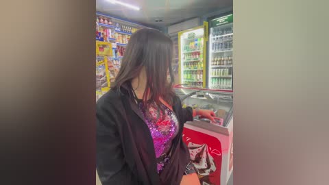 Media: Video of a young woman with long black hair, wearing a black jacket over a purple floral top, shopping in a brightly lit convenience store.