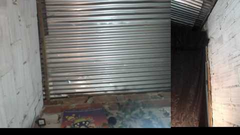 Video of a dimly lit, narrow alleyway with a corrugated metal gate at the top, graffiti-covered walls, and a partially open wooden door at the end, giving a gritty urban feel.