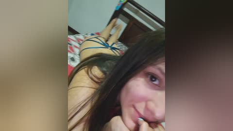 Video of a light-skinned woman with long brown hair, lying on her stomach on a bed in a dimly lit room, wearing blue lingerie.