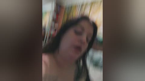 Blurry video of a young woman with dark hair, eyes closed, possibly in a sensual state, with out-of-focus background suggesting an intimate setting.