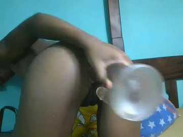 A blurry, low-quality video showing a naked person with a bald head and medium skin tone, bending over with their hand near their anus, in a bedroom with a blue wall and a star-patterned pillow.