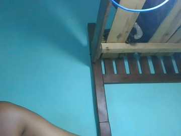 A video showing a wooden shelf attached to a turquoise wall, with a blue power cord hanging from it, and a shadow of a person's arm on the left side.