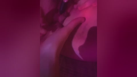 A blurry, pink-hued video with indistinct figures, possibly two people, captured in motion against a dark background, suggesting a sensual or intimate scene.