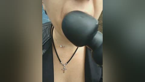 Video of a light-skinned woman with small breasts, wearing a black shirt, black necklace with a cross pendant, and boxing gloves, taken from a close-up, slightly blurred perspective.