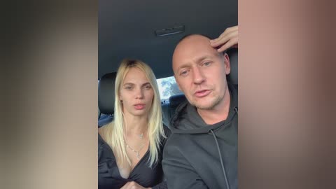 Media: A video captures a blonde woman in a black bra and a bald man in a hoodie sitting in a car.