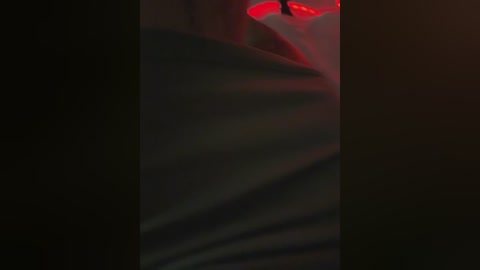A video featuring a close-up view of a person's face, partially obscured by a black mask with red glowing eyes. The image is dimly lit with a dark, moody atmosphere.