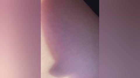 A close-up video of a human ear, featuring a subtle purple and pink hue, with soft lighting creating a diffused, almost dreamlike quality. The ear's skin appears smooth and slightly shiny.