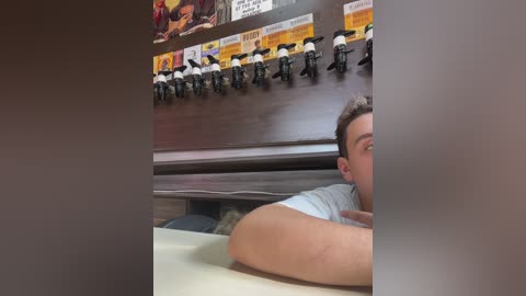 Media: Video of a man in a light blue shirt, leaning on a counter, with a row of beer taps and posters in the background, featuring colorful images of beer bottles.