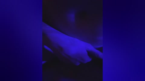 This is a blurred, abstract video with a deep blue background. The image appears to feature a hand holding a white object, possibly a piece of paper or a cloth, with indistinct shapes and shadows. The overall effect is moody and enigmatic.