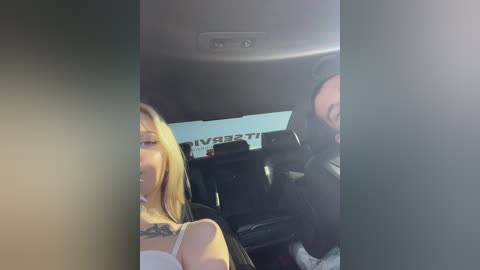 Media: A video of two people in a car: a blonde woman with a tattoo and a man with a beard, both smiling.