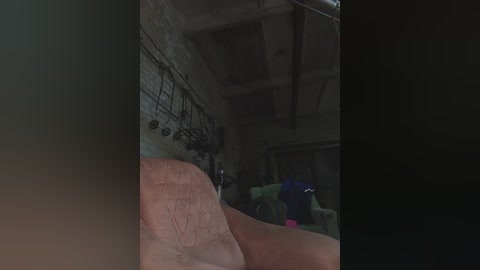 Media: A dimly-lit video of an industrial-style room with exposed brick walls, a metal shelf, and a red couch in the foreground. The background features blurred figures in the shadows, adding an eerie ambiance.