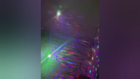 Video of a colorful, reflective surface with a green laser beam and multiple rainbow-colored reflections, set against a dark background. The image captures a vibrant, almost surreal scene.
