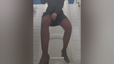 Media: A video of a woman in a black dress, revealing her legs through sheer stockings, standing in a public restroom with white tiled walls and a blue ceiling.