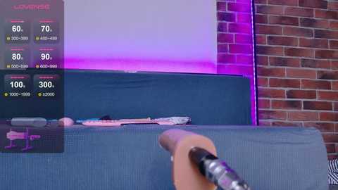 Video of a person holding a controller, aiming at a TV screen displaying a video game interface with stats and purple lighting, set against a brick wall background.