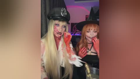 Media: Video of two women in Halloween costumes: one as a cop with a black hat and white wig, the other as a witch with red hair and a black hat. Both have blood on their faces.
