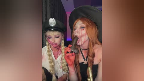 Media: Video: Two women in Halloween costumes, one in a police uniform, the other in a black dress, licking a chocolate cake.