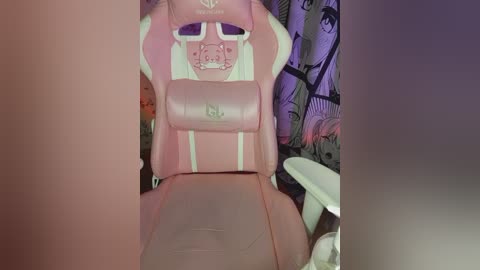Video of a pink, plush gaming chair with white accents and a cat design on the headrest, set against a dark, cartoon-themed backdrop.