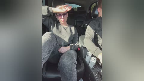 Media: A video of a stylish woman in a black hat, sunglasses, and gray sweater and pants, sitting in the backseat of a car.