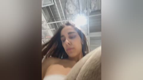 Media: A blurry, low-resolution video of a young woman with medium brown skin and straight, dark brown hair, wearing a white strapless top, taken indoors with a ceiling fan visible.