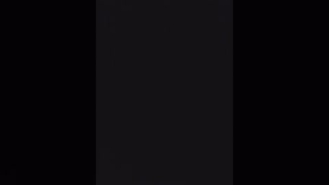 A video of a black flag with a vertical white stripe in the center, set against a pitch-black background. The flag is rectangular, with no other details or text visible.