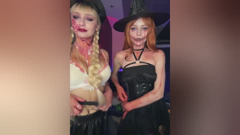 Media: Video of two young women in Halloween costumes: one in a witch hat, black corset, and skirt, and the other in a white lace bra, black hat, and skirt. Both have face paint, and the background is dimly lit.