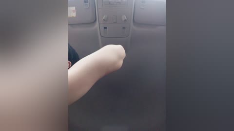 Video of a hand with a small, smooth, shiny object, possibly a coin or key, held above a dark gray car dashboard.