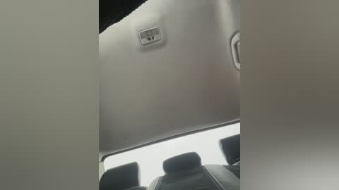 Video of a car interior, showing a gray ceiling with a small, circular vent and a visible headrest in the background. The lighting is soft and diffused, suggesting an overcast day.