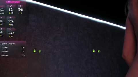 Video of a dimly lit room showing a person's hand holding a smartphone with a bright screen displaying a game interface. The background is dark, with a faintly visible texture, and the phone's screen dominates the frame.