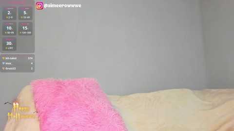 Video of a minimalist bedroom with a pink fluffy pillow on a beige bedspread against a plain white wall. Social media icons and a counter with 15 followers, 1.5k likes, and 1.4k views are visible in the top left.
