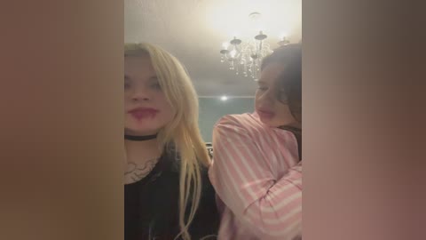 A video of two women in a dimly lit room, one with blonde hair, the other with dark hair, wearing striped pajamas.