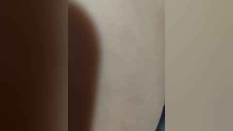 Video of a blurred, close-up human torso with pale skin and slight blemishes, suggesting a natural, unedited appearance. The background is out of focus, with a muted, beige tone.