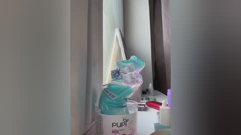 Video of a white Pudin baby formula box with a clear plastic bag containing a baby bottle and a blue pacifier, sitting on a white counter.
