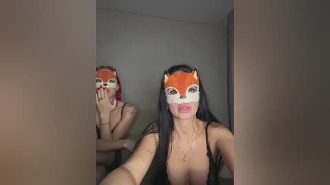 A video of a woman with long black hair, wearing a fox mask and a revealing black top, taking a selfie in a dimly lit room.